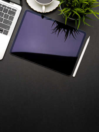 Top view of dark creative flat lay workspace with digital tablet, laptop, plant pot and copy spaceの写真素材