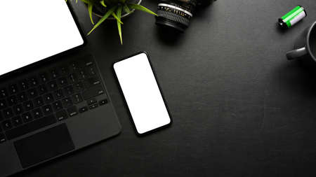 Creative flat lay dark workspace with smartphone, digital tablet, camera and copy space, clipping...