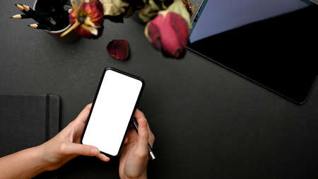 Top view of female hands using smartphone include clipping path screen on black creative workspaceの写真素材