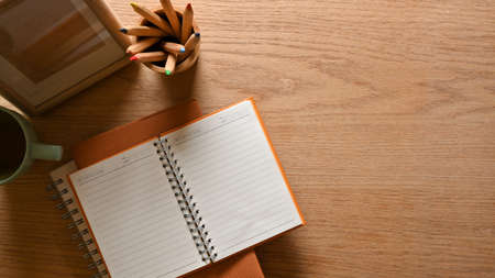 Top view of wooden study table with stationery, cup and copy space, creative flat lat workspaceの写真素材