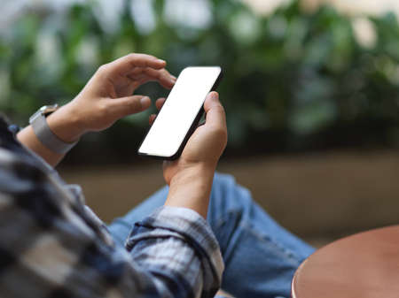 Cropped shot of male freelancer hands using smartphone while relaxing in garden at home, clipping...