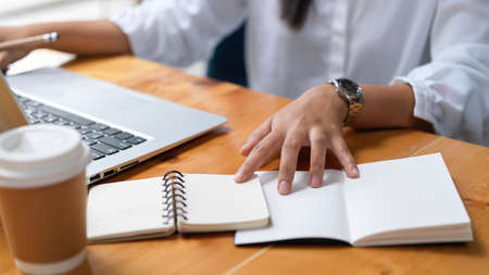 Cropped shot of businesswoman working on her project while using notebook in workspace