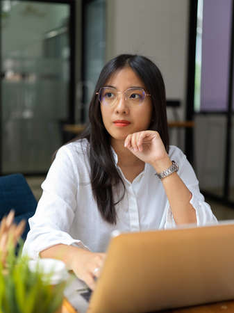 Portrait of young businesswoman looking of the window while thinking about her projectの写真素材