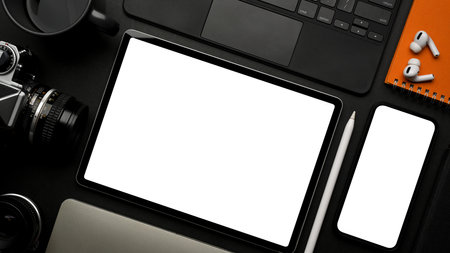 Dark creative flat lay workspace with digital tablet, smartphone and accessories on table, clipping path, top viewの写真素材
