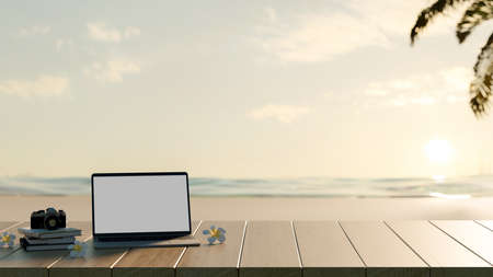 Cropped shot of blank screen mock up laptop computer with book and camera on wooden table with sea background, copy spaceの写真素材