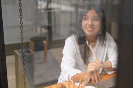 Portrait of young businesswoman looking of the window while thinking about her projectの写真素材
