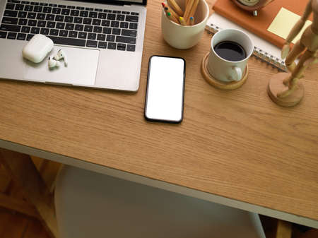 Top view of workspace with smartphone, laptop, coffee cup and stationery on the table, clipping path