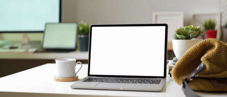 Close up view of workspace with mock up laptop, bag, cup and decorations in blurred office room background, clipping pathの写真素材