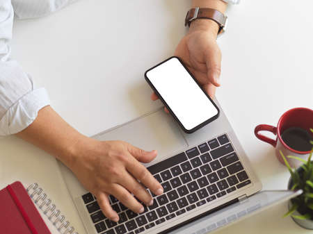 Overhead shot of businessman working with laptop and smartphone on white desk, clipping path