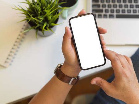 Top view of businessman hands using smartphone with mock up screen on workspace, clipping pathの写真素材