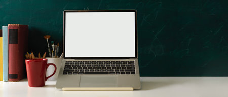 Close up view of study table with laptop, stationery, books and copy space on white desk with...