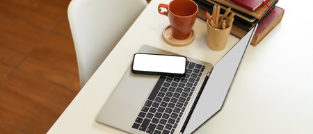 Side view of simple workspace with laptop, smartphone, stationery, stack of books and mug on white desk, clipping pathの写真素材