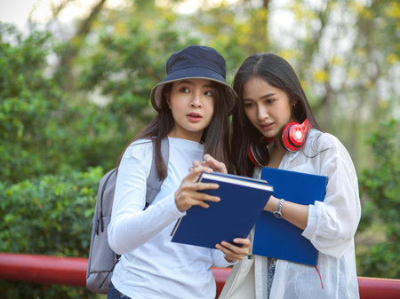 Half- length portraits of two female university students with school elements outdoor study at park in universityの写真素材