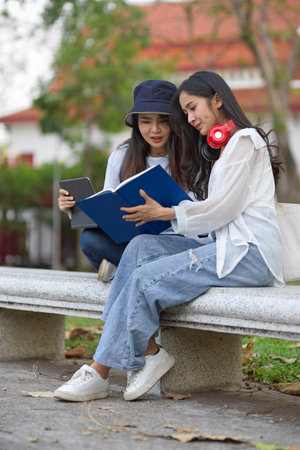 Cropped shot of female university students outdoor study, reading books together at the park in universityの写真素材