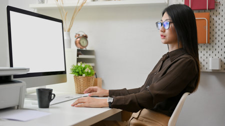 Side view of female office worker concentrate on her work with computer device in modern office room, clipping pathの写真素材