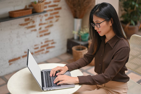 Portrait of female freelancer working with mock up laptop on round table in coffee shopの写真素材