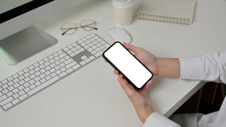 Side view of female hand using smartphone include clipping path screen on computer tableの写真素材