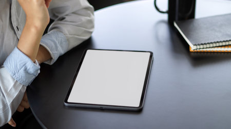 Close up view of young female using mock up blank screen digital tablet while working on her projectの写真素材
