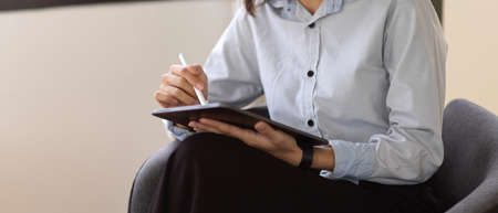 Cropped shot of young female writing her idea on digital tablet in office roomの写真素材