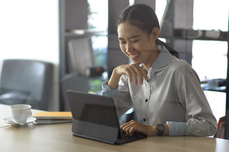 Portrait of young professional businesswoman working on her project while using digital tabletの写真素材