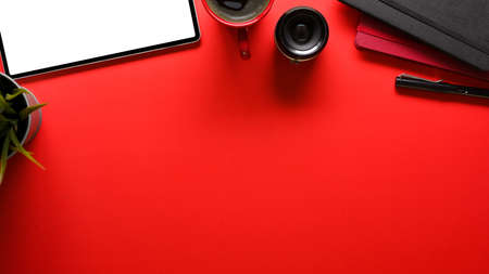Top view of working table with tablet and office supplies on bright red table background, clipping pathの写真素材
