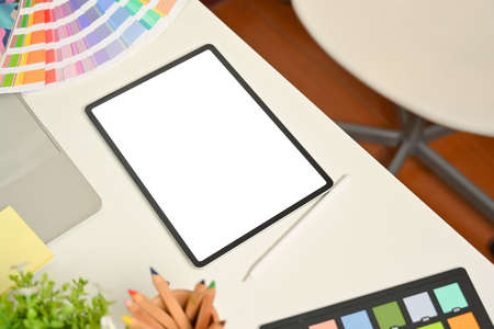 Cropped shot of designer workspace with digital tablets, coloured pencils and colour swatch on white desk, clipping pathの写真素材