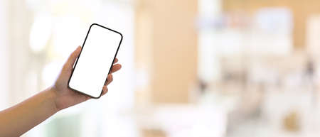 Close up view of woman hand holding smartphone and showing mock up screen to camera in blurred background, clipping pathの写真素材