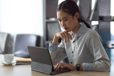 Cropped shot of female office worker concentrating on her work with digital tablet in meeting roomの写真素材
