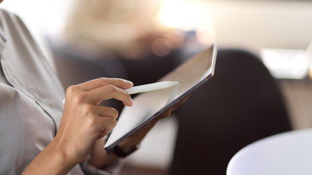 Cropped shot young businesswoman writing on digital tablet while sitting in the office roomの写真素材