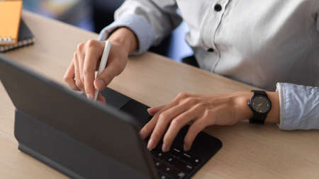 Cropped shot of young female working with digital tablet in office roomの写真素材