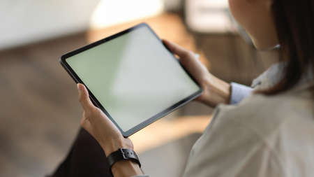 Cropped shot of young female holding mock up blank screen digital tablet while workingの写真素材