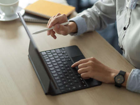 Cropped shot of young female working on her project with digital tablet in office roomの写真素材