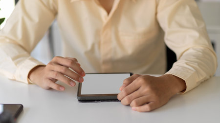 Close up view of businessperson hands working with mock-up tablet on simple office deskの写真素材