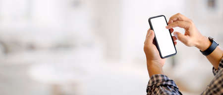 Cropped shot of a man hands using mock up smartphone in blurred background, clipping pathの写真素材