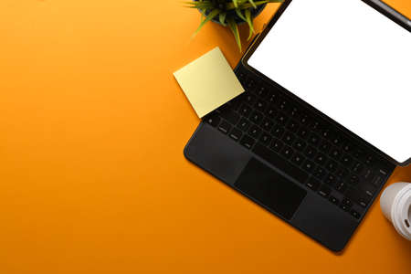 Top view of creative workspace with digital tablet, keyboard, notepad and copy space on yellow background, clipping pathの写真素材