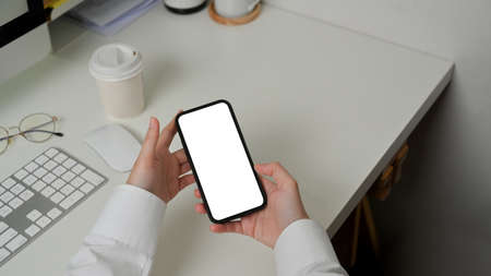 Close up view of female using smartphone include clipping path screen in her hands at workplaceの写真素材
