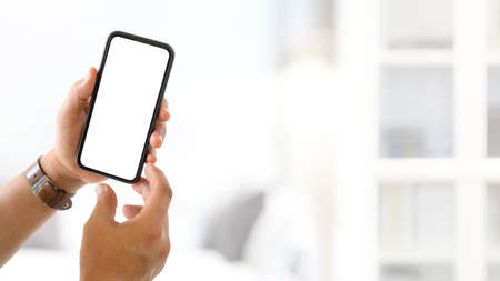 Cropped shot of hand man holding blank screen mock up smartphone with blurred backgroundの写真素材