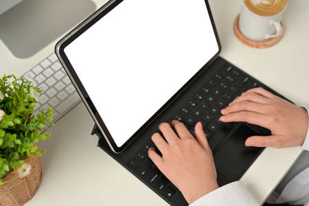 Cropped shot of female hands typing on tablet keyboard on white table in home office room, clipping pathの写真素材