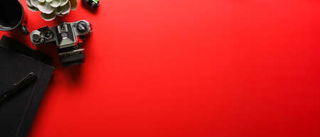 Top view of creative flat lay workspace with camera, office supplies and copy space on red desk backgroundの写真素材