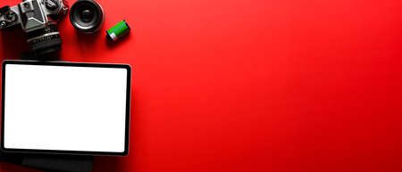 Overhead shot of bright red photographer desk with office supplies and mock up tablet with clipping pathの写真素材