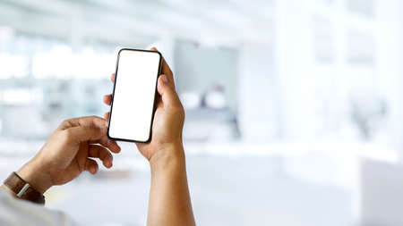 A man hands holding and showing mock up smartphone screen to camera in blurred background, clipping pathの写真素材