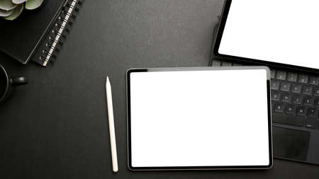 Top view of dark workspace with two tablets, accessories, stationery and copy space, clipping pathの写真素材