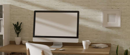 3D rendering, home office room with computer, mug and decoration on wooden table with brick wall, 3D illustrationの写真素材