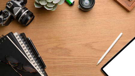 Top view of mock up scene, workspace with tablet, stationery, books, camera and copy space