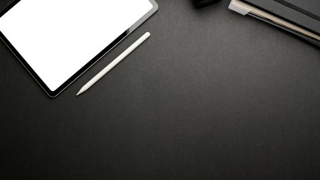 Dark creative flat lay workspace with digital tablet, stylus and copy space on black table, mock up sceneの写真素材
