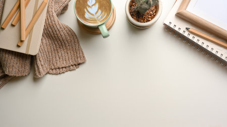 Top view of simple study table with sweater, stationery, books, coffee cup, cactus pot and copy spaceの写真素材