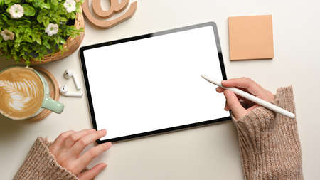 Overhead shot of female hands using mock up digital tablet with stylus pen on white desk, include clipping pathの写真素材