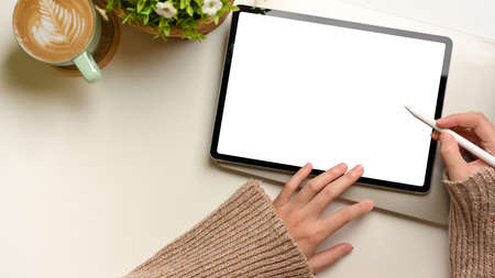 Top view of female hands using mock up digital tablet with stylus pen on white desk, clipping pathの写真素材