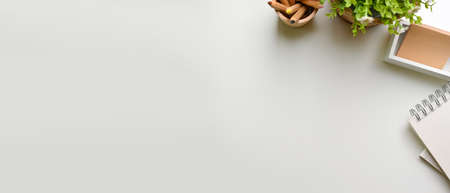 Creative flat lay workspace with stationery, plant pot and copy space on white background, top viewの写真素材