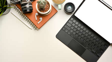 Creative flat lay workspace with digital tablet, camera, notebook and copy space on white desk, top viewの写真素材